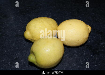 multiple lemons on a dark kitchen worktop. Stock Photo