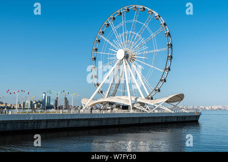 Baku, Azerbaijan - May 12, 2019. Baku Eye ferris wheel in Baku, Azerbaijan, across the water, with people. Stock Photo