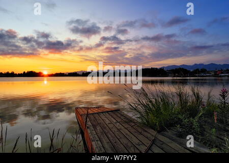 Sunrise at lake Hood seaplane base with jetty, flowers and mountains in Anchorage, Alaska, USA Stock Photo