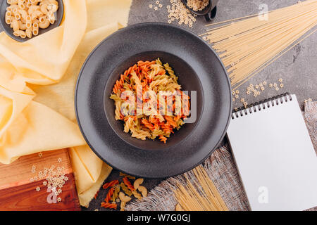 Different types of pasta on a black plate top view. Stock Photo