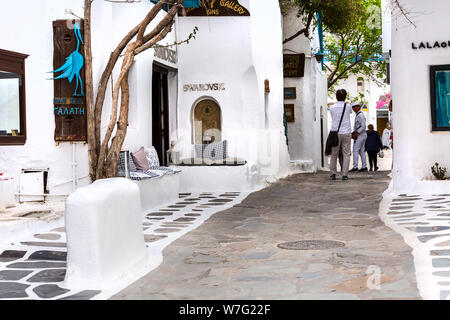 Mykonos, Greece - April 23, 2019: Famous island street view with white houses and people in Cyclades Stock Photo