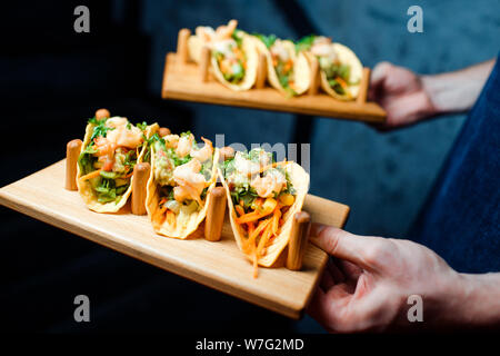 Shrimp appetizers with vegetables and herbs on a wooden plate in a beer bar. Stock Photo