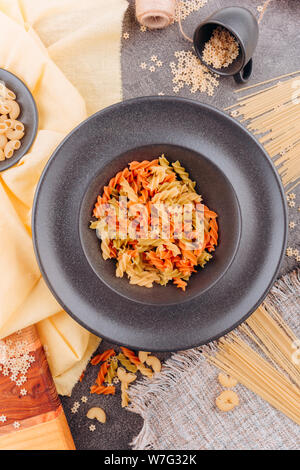 Different types of pasta on a black plate top view. Stock Photo