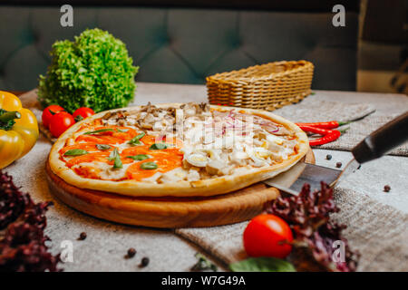 Sliced delicious tasty pizza with vegetables on wooden table. Stock Photo