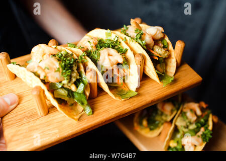 Shrimp appetizers with vegetables and herbs on a wooden plate in a beer bar. Stock Photo