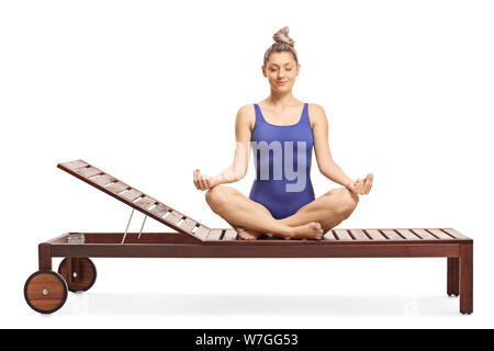 Young woman sitting on a lounge chair practicing meditation isolated on white background Stock Photo