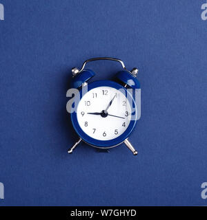 Alarm clock on dark blue background. Minimal styled photo. Stock Photo