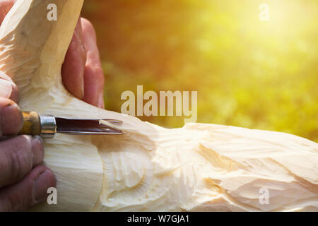 Old man hands with cutter for wood carving. Handmade concept. Nature background with copy space. Sunlight Stock Photo