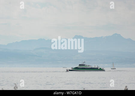 A tour boat passes the Alps on Lake Constance (Bodensee) before coming into the harbor on a summer day in Friedrichshafen, Germany. Stock Photo
