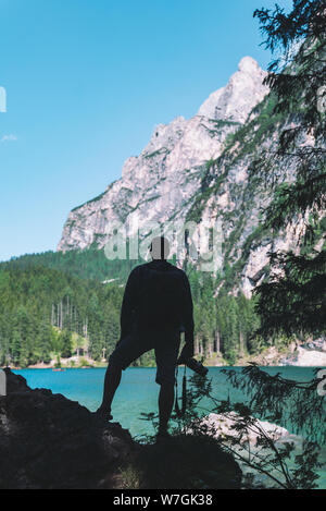 man climbing by rocks to shoot beautiful landscape of lake and mountains. photographer activities Stock Photo