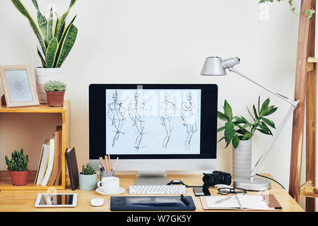 Workplace of illustrator with line female figures on computer screen, planners, plans and devices Stock Photo