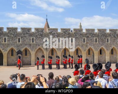 Tourists watch soldiers of the Household Troops during the changing the Castle Guard ceremony in Windsor Castle Lower Keep precincts, Windsor, UK Stock Photo