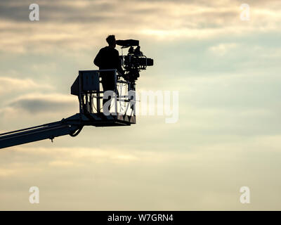 A Television Cameraman stands on a Cherry Picker Crane as he films a Horse Racing meeting at Musselburgh Racecourse, East Lothian, Scotland, UK. Stock Photo
