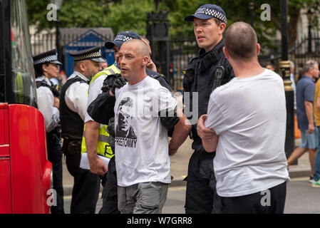 Arrested protester at Free Tommy Robinson protest rally In London, UK. Police leading away white Caucasian male under arrest. Free Tommy shirt Stock Photo