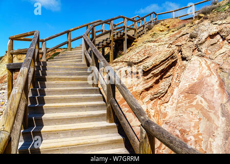 Wooden stairs with handrails leading up and right to the top of an orange rock, viewpoint, blue sky, some clouds, - horizontal landscape format Stock Photo