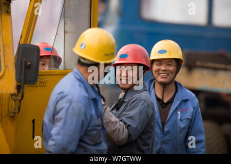 Portrait of a mid-adult construction worker with two mid-adult co-workers at a shipping yard. Stock Photo