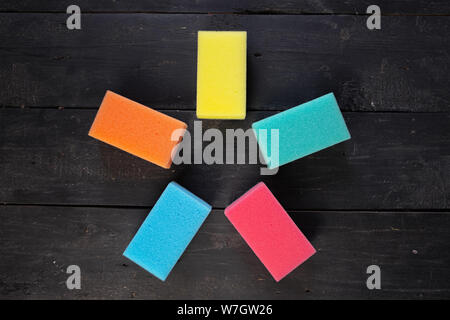 Sponges form a pentagon star shape, top view. Five pieces of dishcloth on dark background, shot from above Stock Photo