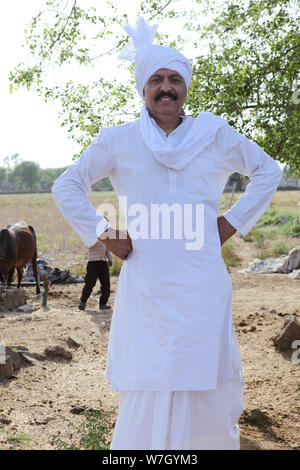 Rural man standing with his arms akimbo Stock Photo - Alamy