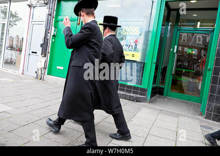 Rear view of two Hasidic Jewish men walking along Stamford Hill high street in North London N16 England UK  KATHY DEWITT Stock Photo