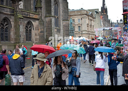 Edinburgh, Scotland, UK 6th August 2019. Very wet early morning turning into a dull overcast day until heavy rain showers arrived at 4pm on the Royal Mile to dampen Fringe spirits it was busy with umbrellas. Patrick the 12 year old street performer juggling fire on the High Street and the musical buskers on George the 1V Bridge did not let this disturb their performances. Stock Photo