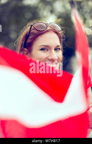 Happy young redhead woman waving Austrian flag closeup, depth of field, selective focus Stock Photo