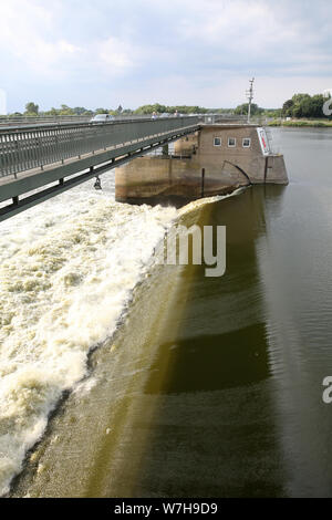 06 August 2019, Lower Saxony, Rönne: Water flows over the Elbe dam at Geesthacht. Since 02.08.2019, water had to be drained in order to reduce the water pressure on the structure and to relieve the dam. As a result, the water level dropped and shipping had to be stopped. Photo: Bodo Marks/dpa Stock Photo