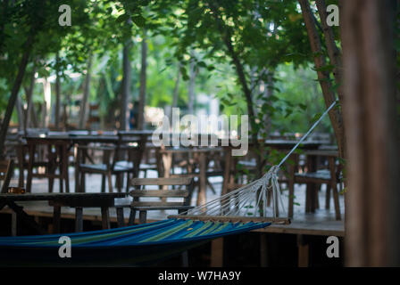 Relaxing zone in a bar, hammock tied by the tree. Stock Photo