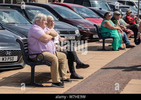 A middle aged couple sat on a bench at the seaside Stock Photo
