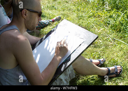 Kharkiv, Ukraine - July 09, 2019: Top view guy makes a watercolor sketch on an outdoor plein air Stock Photo