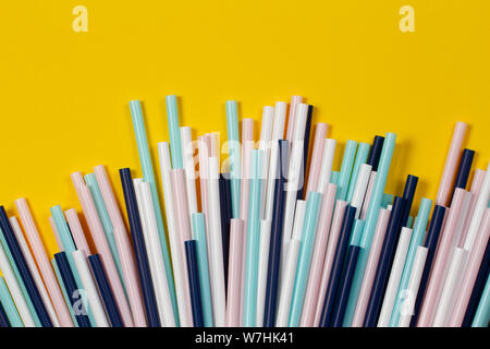 Multicolored cocktail tubes straws on yellow background Stock Photo