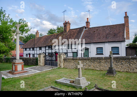 Half timbered black and white cottages in the village of Pangbourne in West Berkshire, UK beyond the churchyard of St James the Less Church. Stock Photo