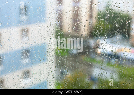 rain drops on windowpane and blurred city on background on rainy autumn evening Stock Photo