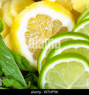 food background - cocktail ingredients, slices of fresh limes, lemons and ginger with green mint leaves close-up Stock Photo