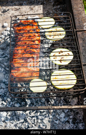 cooked pork ribs with sliced squash vegetable in outdoor charcoal grill Stock Photo