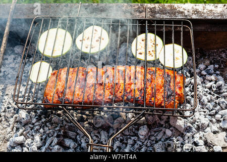 cooked pork ribs with sliced zucchini vegetable in outdoor charcoal grill Stock Photo