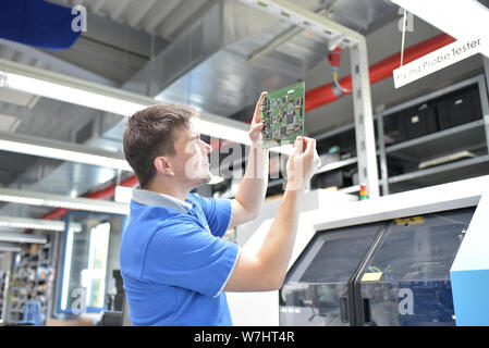 engineering in microelectronics: workers in the production and quality control  of electronic high tech components in a modern factory Stock Photo
