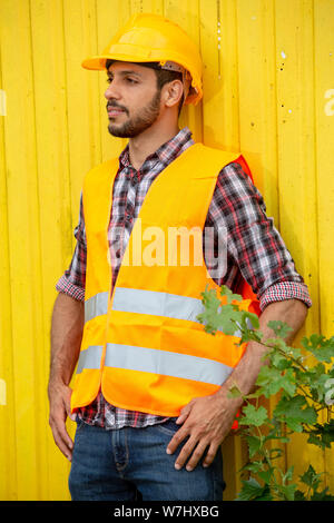 handsome construction worker with yellow helmet and orange vest Stock Photo