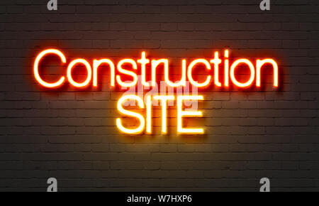 Construction site neon sign on brick wall background Stock Photo