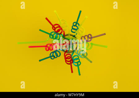 Spiral colorful straws on yellow background, flat lay Stock Photo