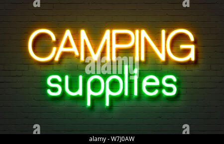 Camping supplies neon sign on brick wall background Stock Photo