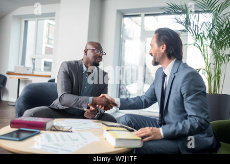 Dark-skinned businessman shaking hand of his economist after consultation Stock Photo