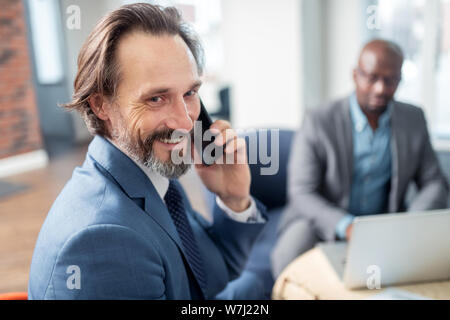 Businessman feeling happy receiving call from wife while working Stock Photo