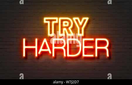 Try harder neon sign on brick wall background Stock Photo