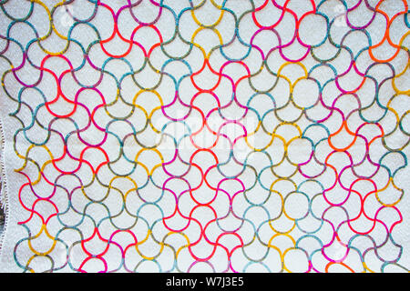 Beautiful white fabric with colorful patterns. Patterns of bright colors intertwined in red, blue and yellow. Stock Photo