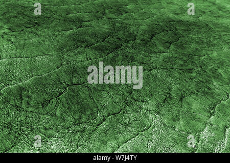 Empty abstract background naturally created by small sea waves in shallow waters and sunlight reflections on water surface. Toned in blend of dark gre Stock Photo