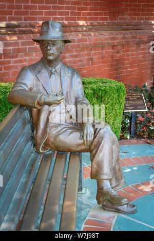 Bronze plaque and statue of William Faulkner seated on a bench with hat and pipe near City Hall in his hometown of Oxford, MS, USA Stock Photo