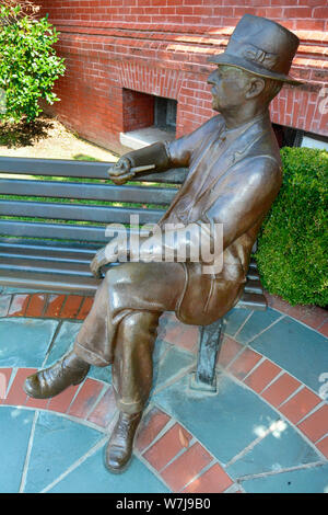 Bronze statue of William Faulkner seated on a bench with hat and pipe near City Hall in his hometown of Oxford, MS, Stock Photo