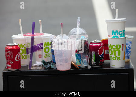 Waste packaging of fast food, tin drink cans, plastic cups, straws, left outside on the top of a  box in London. Stock Photo