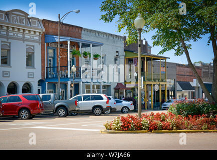 Red and white flowers on the Courthouse  Square are Lovely before the old brick builidings now housing shops and retail and offices around the court h Stock Photo