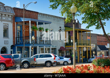 Red and white flowers on the Courthouse  Square are Lovely before the old brick builidings now housing shops and retail and offices around the court h Stock Photo